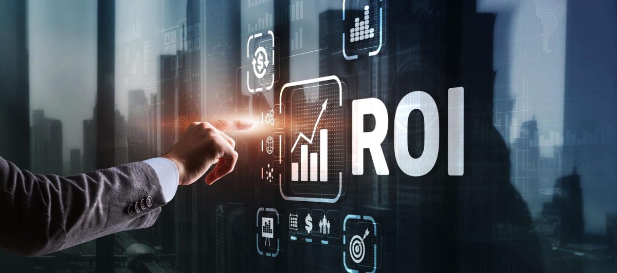 Egy kéz megérint egy virtuális felületet, amelyen a "ROI" felirat és különböző üzleti ikonok, például diagramok és pénzügyi szimbólumok láthatók, modern irodai környezetben.