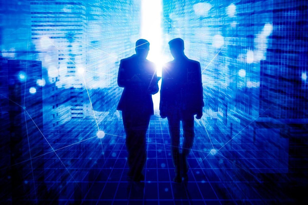 Két üzletember sziluettje digitális, kék háttérben, fénylő adathálózattal és városi épületekkel. A jövő technológiai kihívásai.