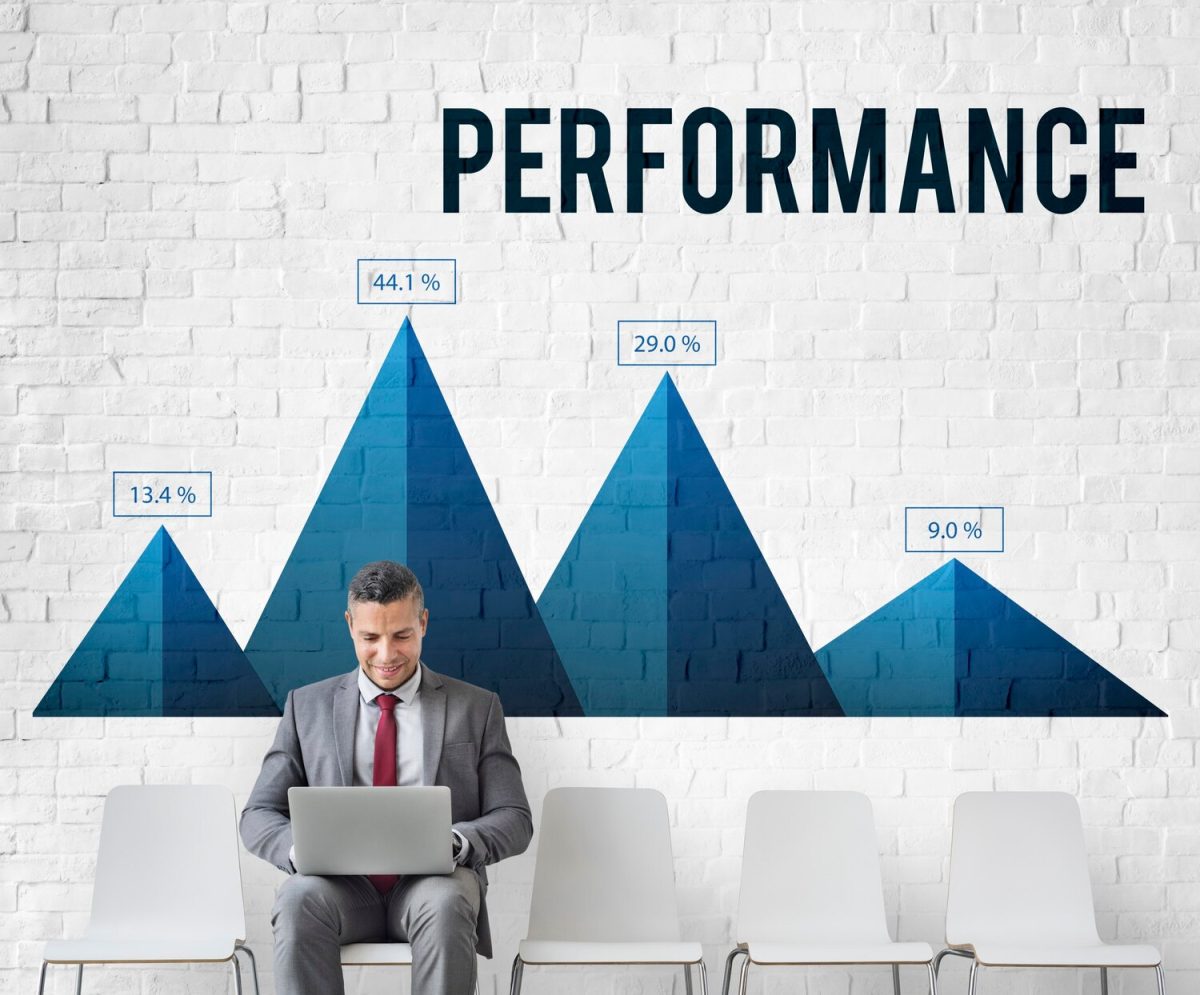 Üzletember laptopot használ, miközben egy növekedési grafikont ábrázoló "PERFORMANCE" felirat látható a háttérben, százalékos adatokkal.