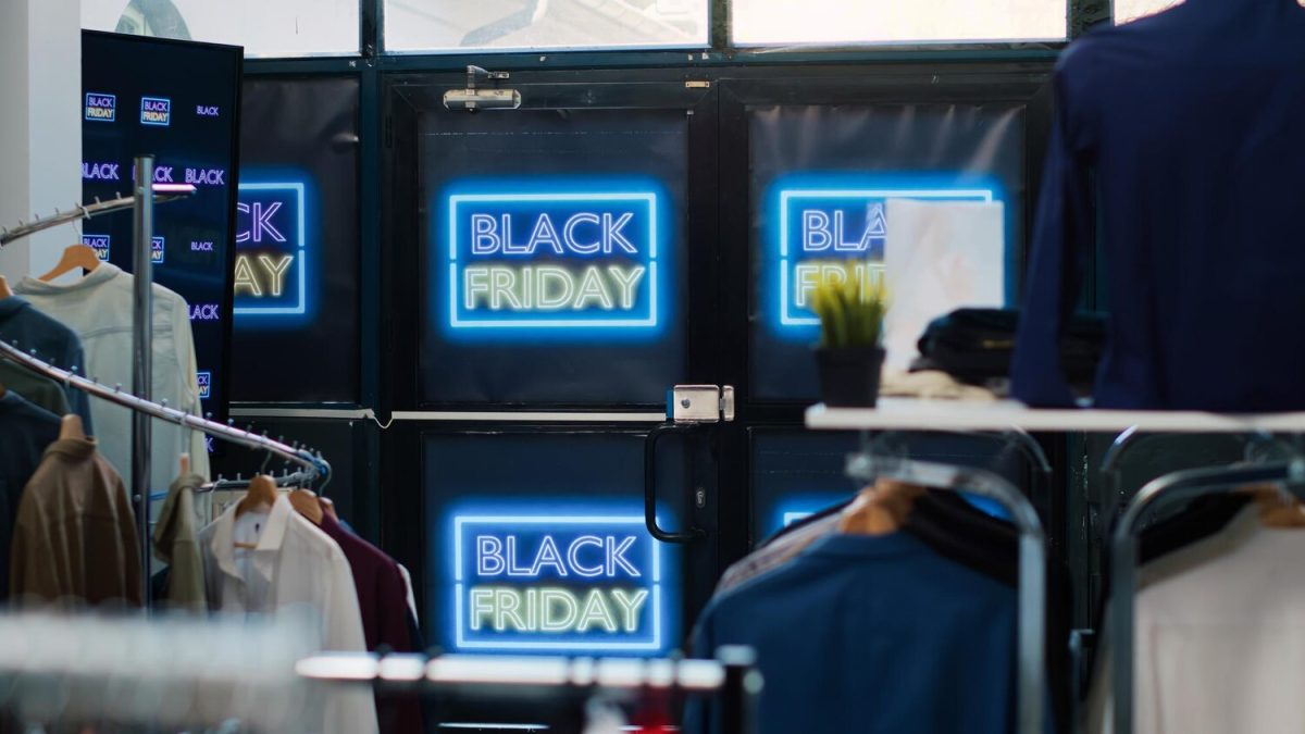 Ruhabolt bejárata kék neonfényű Black Friday feliratokkal és ruhaállványokkal