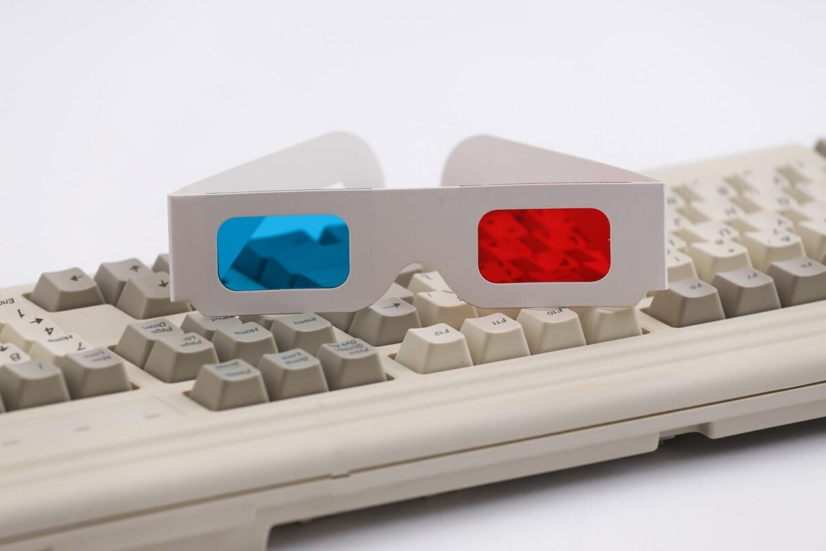 Piros-kék 3D-szemüveg egy klasszikus számítógép-billentyűzeten, fehér háttér előtt.
