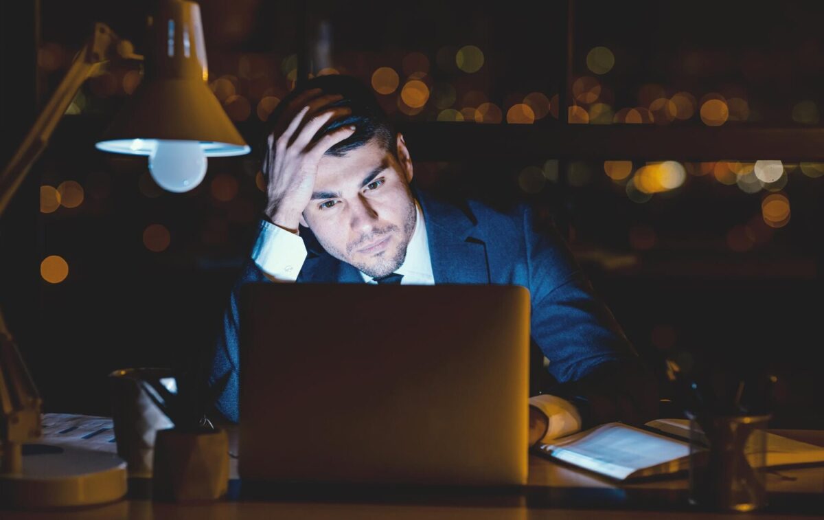 Stresszes üzletember éjszaka a laptopja előtt ül az irodában